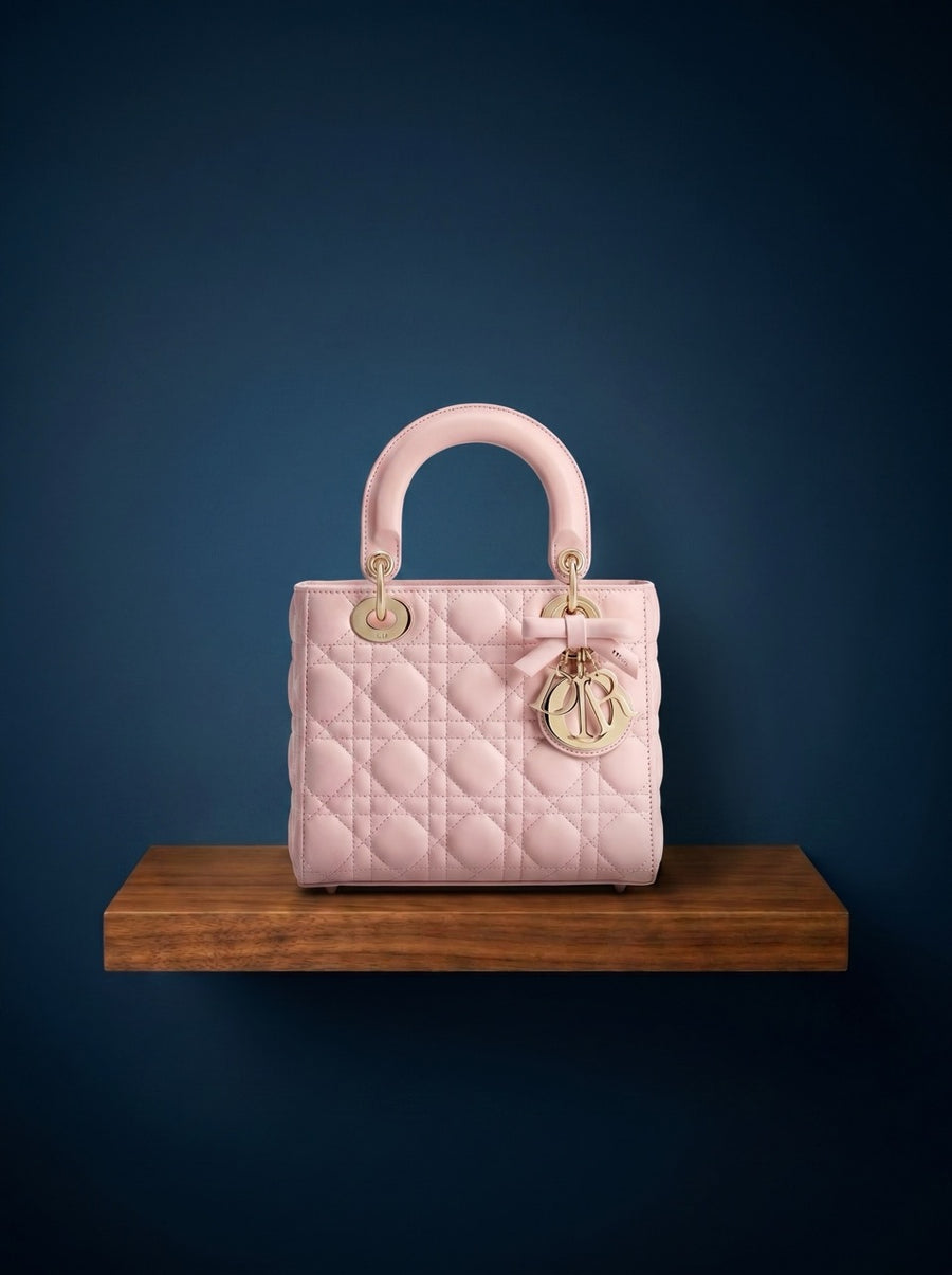 Dior Lady Dior Handbag Pink quilted handbag with gold hardware on a wooden stand against a dark blue background